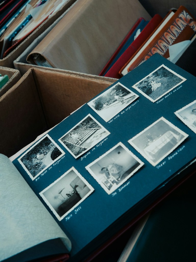 An opened photo scrapbook rests atop opened boxes containing other scrapbooks.